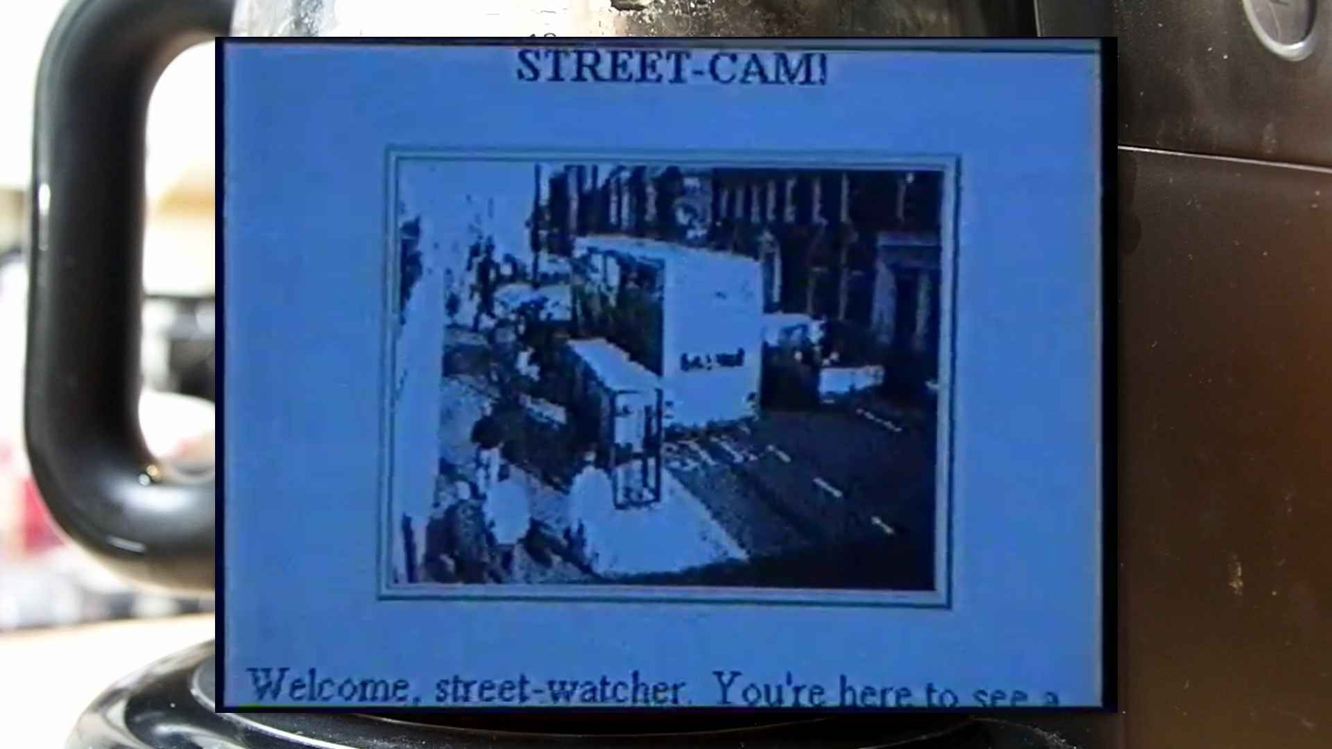 "Street-Cam!" showing a bus stop, in some English town.