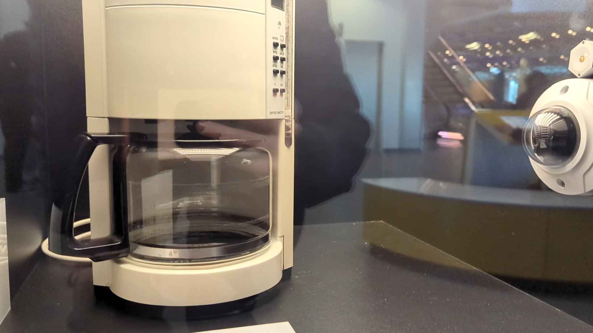 The Krups coffee pot, as seen in the museum, behind glass, and with a webcam to its right